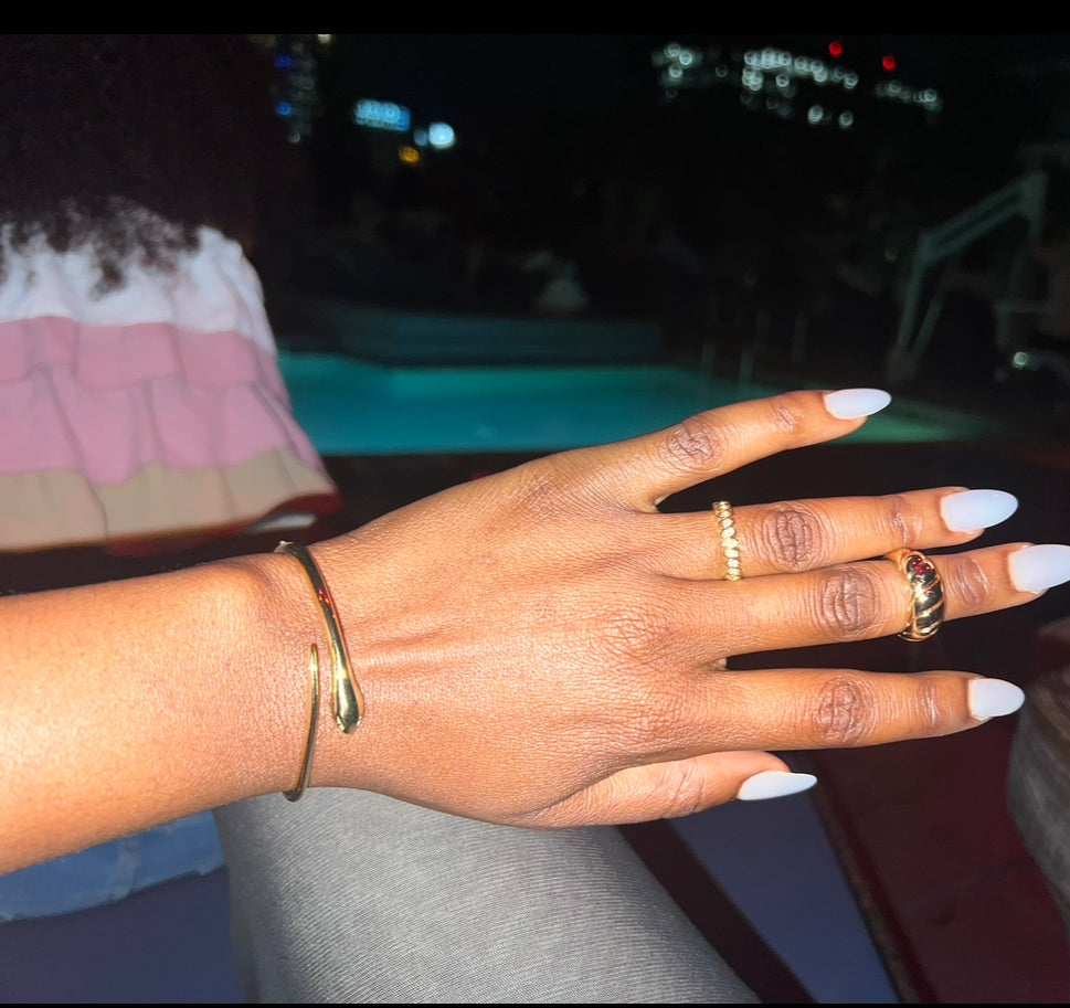 Hand with gold rings and bracelet against a blurred background