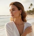 Woman wearing gold earrings with a beach background
