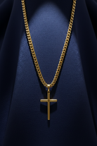 Gold chain necklace with a cross pendant on a dark blue background