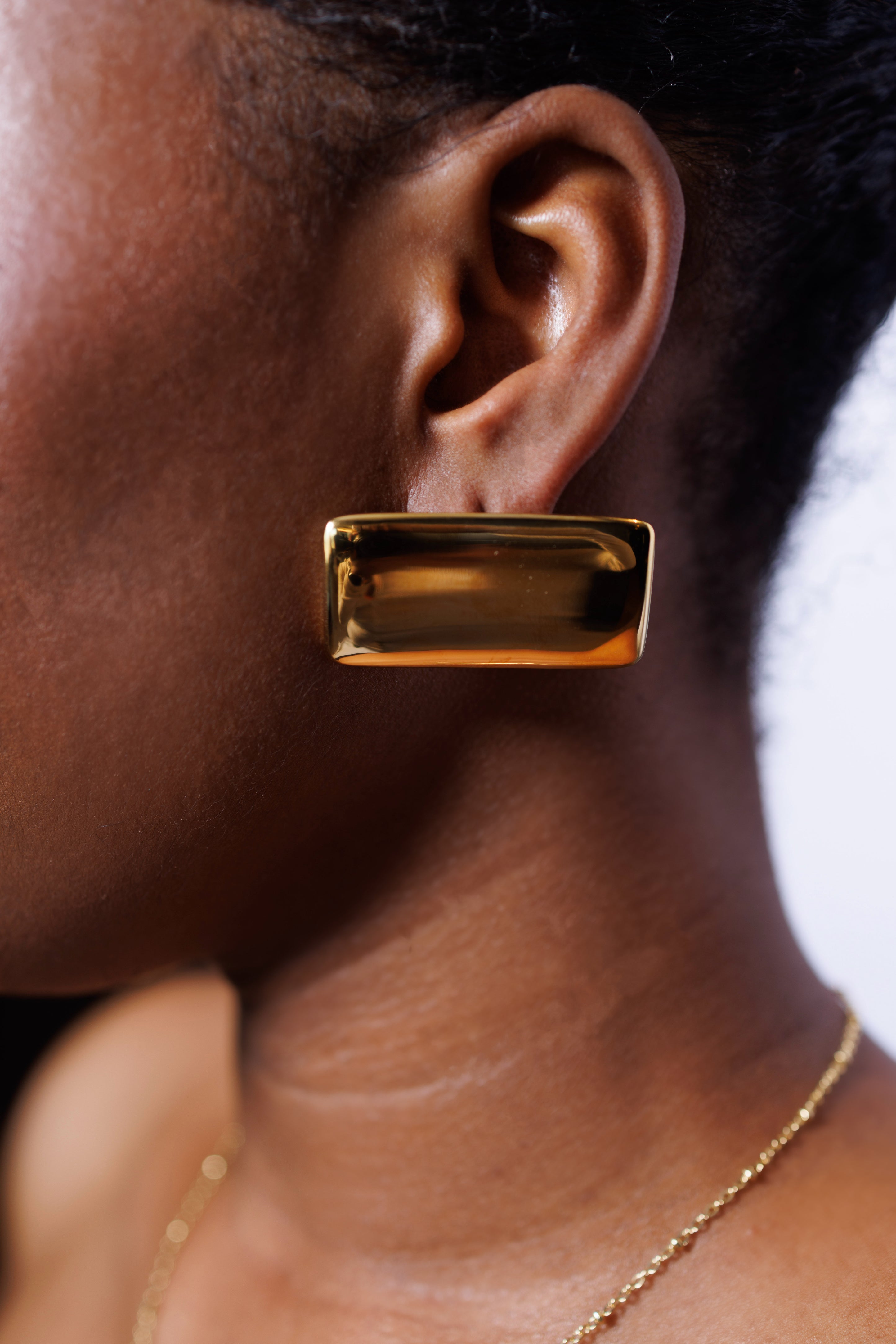 Gold earring worn by a person with a blurred background