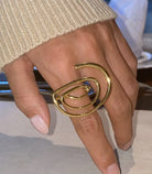 Gold spiral ring on a hand with a blurred background