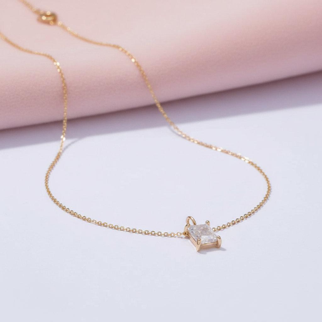 Gold necklace with a diamond pendant on a light pink background