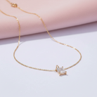 Gold necklace with a diamond pendant on a light pink background