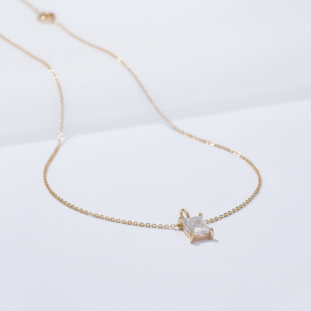Gold necklace with a square-cut diamond on a white background