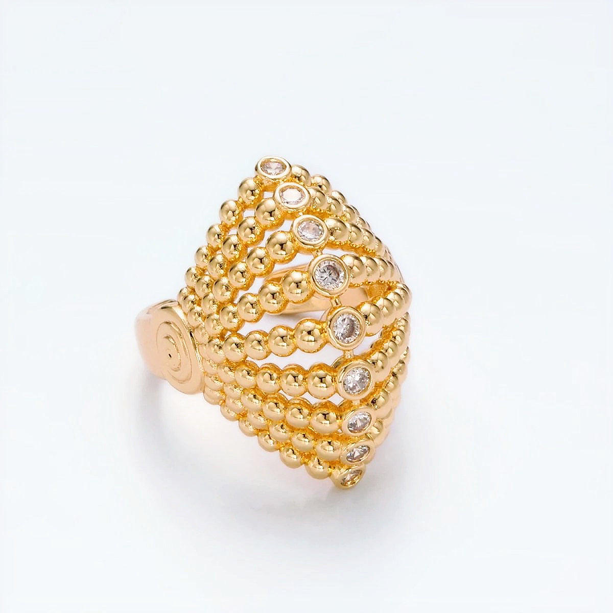 Gold beaded ring with embedded diamonds on a light gray background