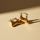 Gold hoop earrings on a beige background
