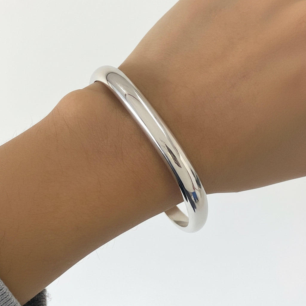 Silver bracelet on a wrist against a white background