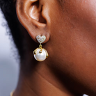 Close-up of an ear wearing a pearl earring with a heart-shaped top.
