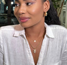 Woman wearing a white shirt with gold jewelry indoors