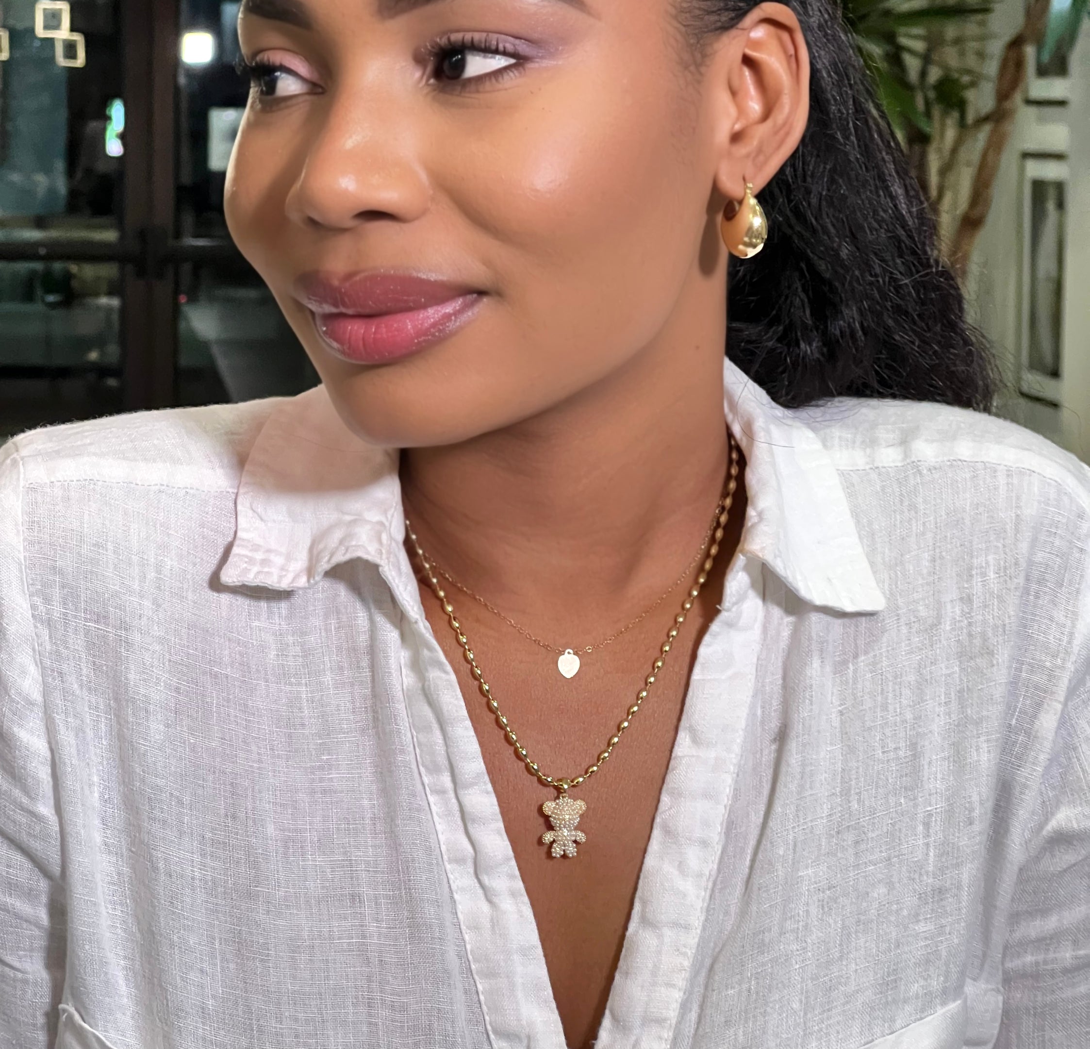 Woman wearing a white shirt with gold jewelry indoors