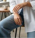 Person wearing a white shirt and blue jeans sitting indoors with a blurred background
