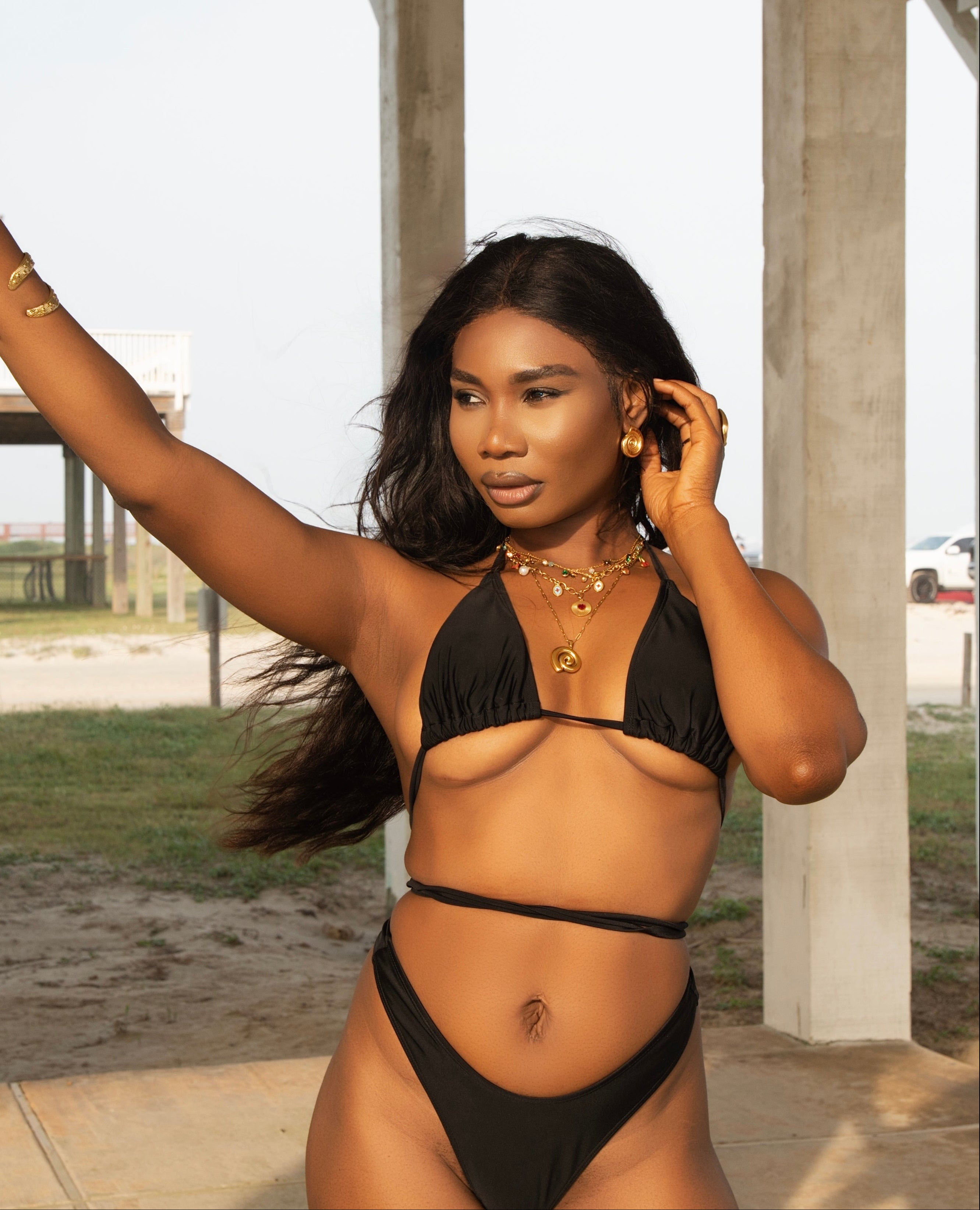 Woman in a black bikini standing outdoors with a neutral background