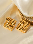 Pair of gold earrings on a beige satin surface