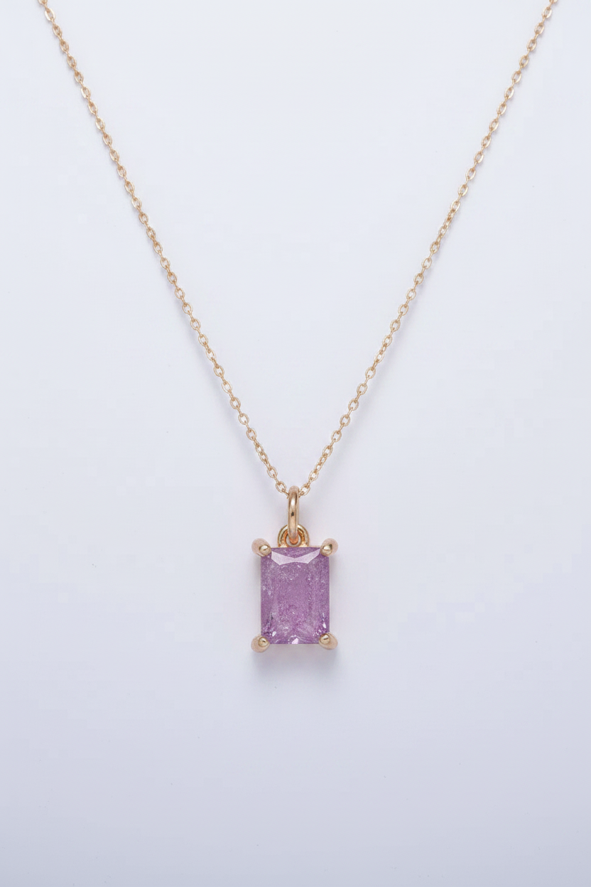 Gold necklace with a purple gemstone pendant on a light gray background