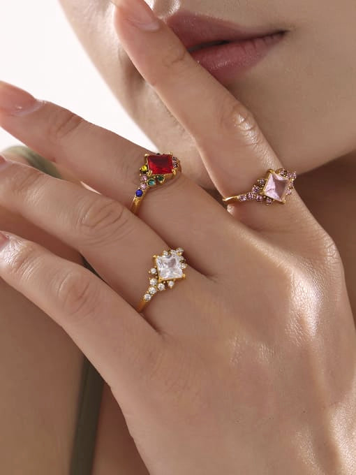Close-up of a hand wearing three rings with gemstones on a neutral background