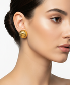 Close-up of a woman wearing gold earrings with a plain background