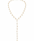 A close-up lifestyle shot of a model wearing a deep plum halter top with a plunging V-neckline, styled with a delicate gold Y-necklace featuring small clear crystal charms.