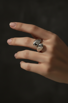 Hand wearing a silver ring on a dark background