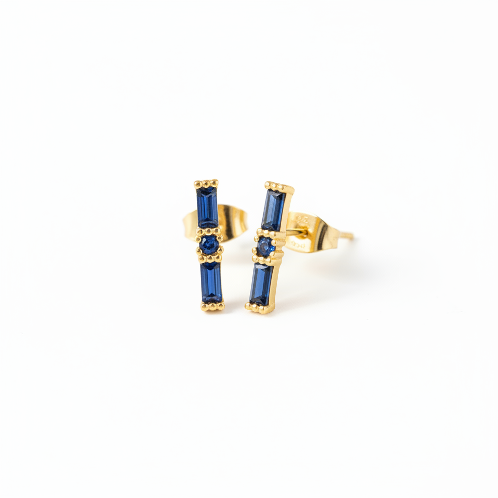 Gold earrings with blue gemstones on a white background