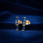 Gold and blue earrings on a dark blue fabric background