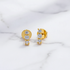 Gold earrings with clear gemstones on a marble surface