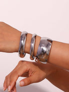 Silver bangles on a wrist against a light background