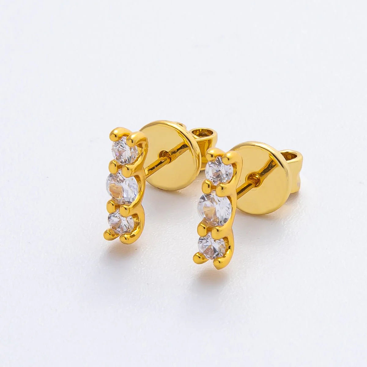 Gold earrings with clear stones on a white background
