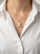 Gold necklace with a teddy bear pendant on a mannequin wearing a white shirt.