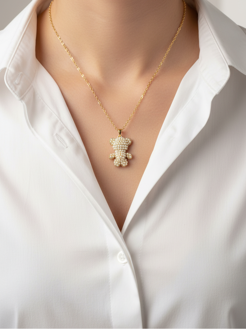 Gold necklace with a teddy bear pendant on a mannequin wearing a white shirt.