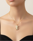 Gold necklace with a teddy bear pendant worn by a model on a neutral background