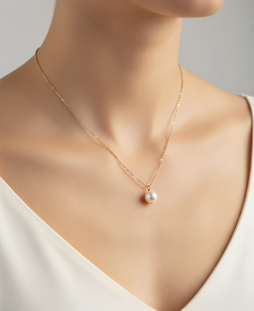 Gold necklace with a single pearl pendant on a white background