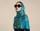 Woman wearing a blue floral scarf and sunglasses on a beige background