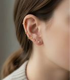 Close-up of a person wearing gold earrings with small stones.