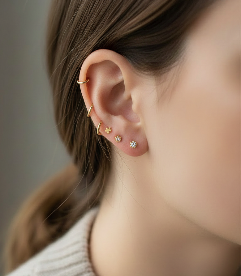 Close-up of a person wearing gold earrings with small stones.