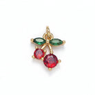 Gold pendant with red and green gemstones on a light gray background