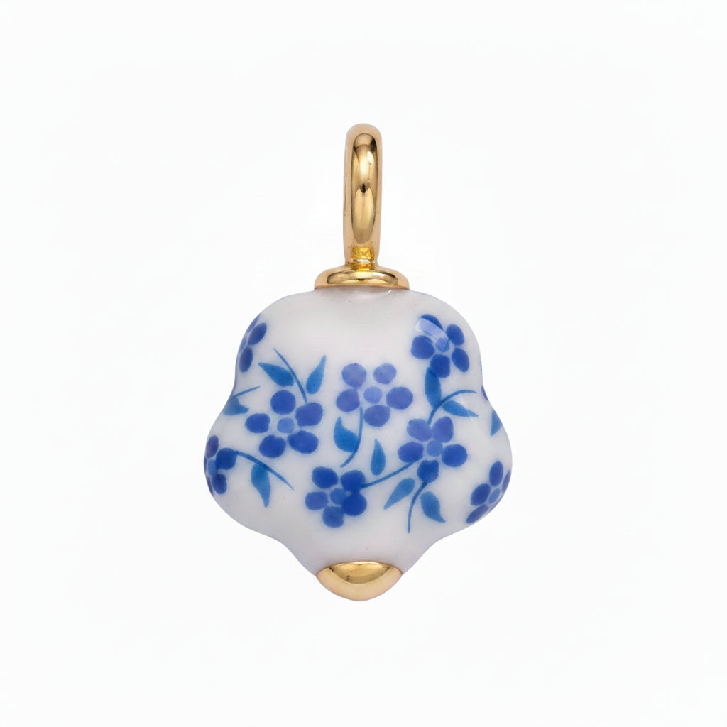 White ceramic pendant with blue floral patterns and gold accents on a light purple background