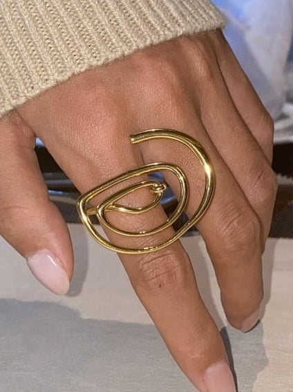 Gold spiral ring on a finger with a neutral background