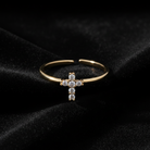 Gold ring with a cross design on a black velvet background