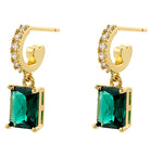 Gold hoop earrings with green gemstones on a white background