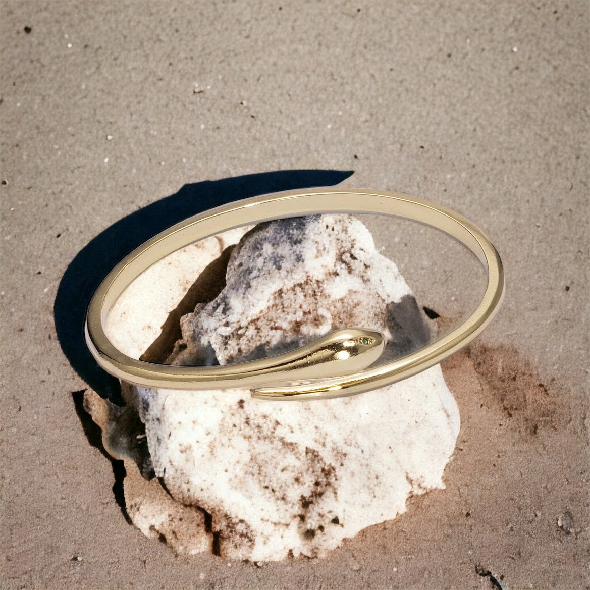 Gold bangle on a rock with a sandy background