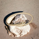 Gold bangle on a rock with a sandy background