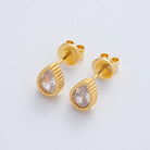 Gold earrings with clear gemstones on a light gray background