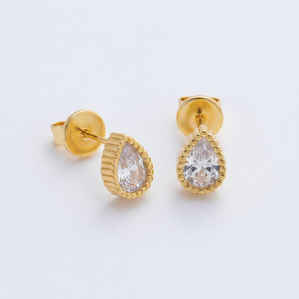 Gold earrings with teardrop-shaped gemstones on a light gray background