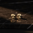 Gold mushroom-shaped earrings with small stones on a light gray background