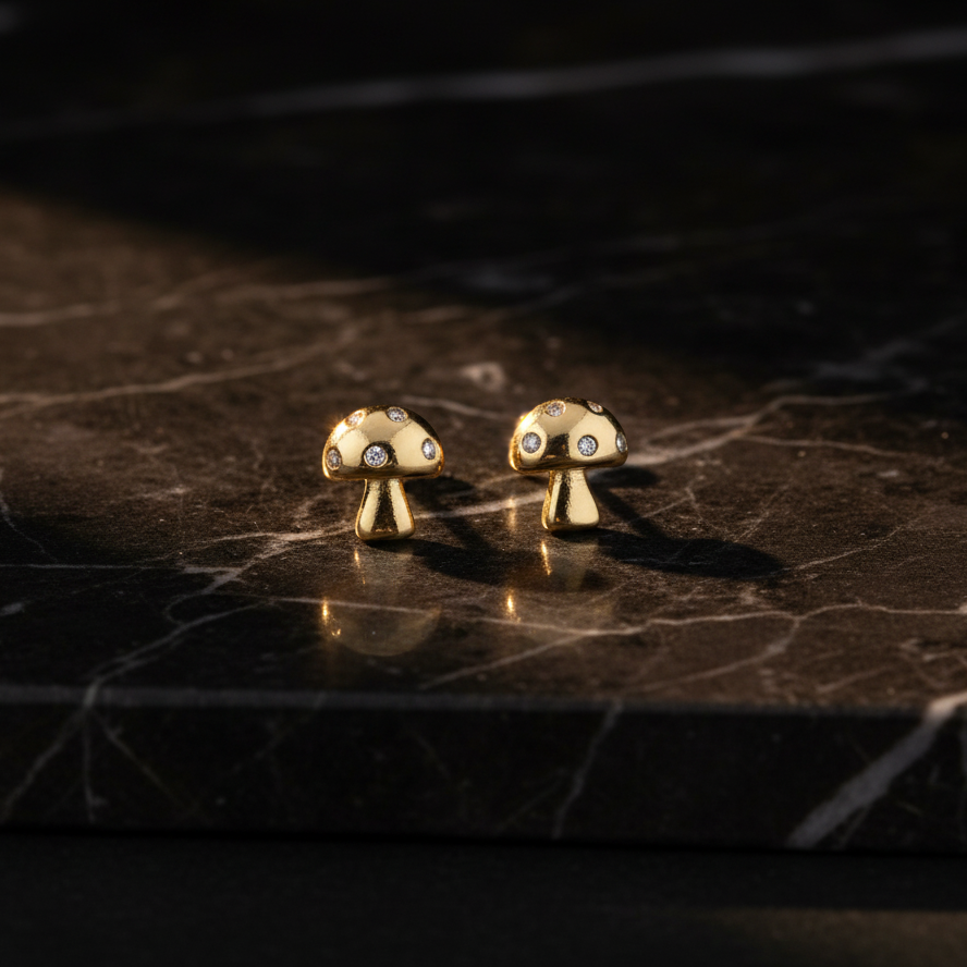 Gold mushroom-shaped earrings with small stones on a light gray background