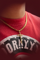 Gold chain necklace with a cross pendant on a dark blue background