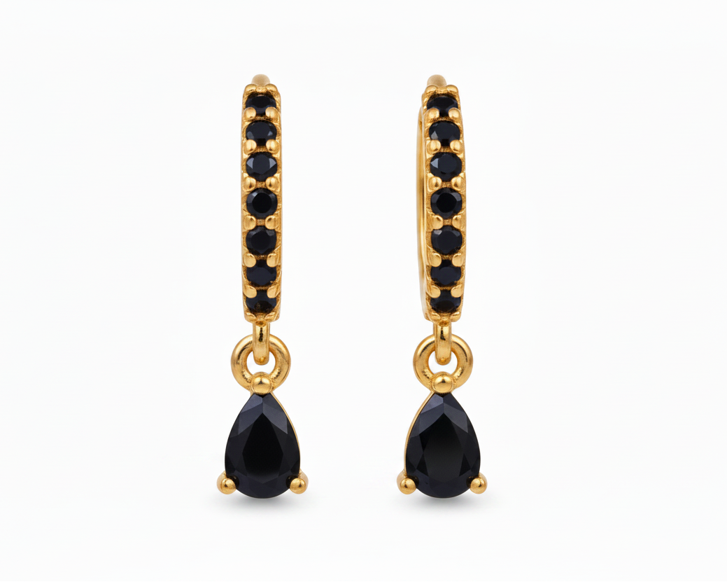 A pair of gold huggie hoop earrings with small black stones along the front and a teardrop-shaped black gemstone dangling from the center, shown on a plain white background.