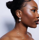 Woman wearing pearl earrings and necklace against a plain background