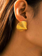 Gold earring worn by a person with brown hair.