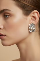 Close-up of a woman wearing a silver earring against a neutral background